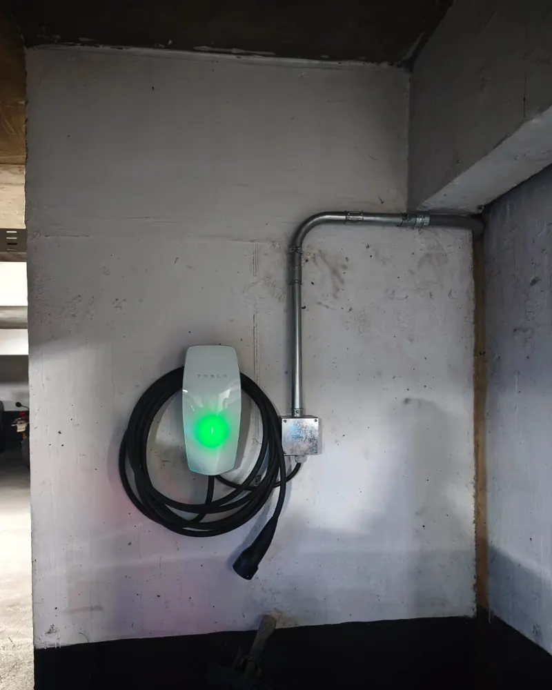 Wall Connector de Tesla encendido en un estacionamiento subterráneo, con canalización metálica EMT
